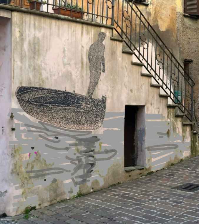 Murale di un uomo in piedi su una barca, dipinto su un muro di una strada acciottolata.