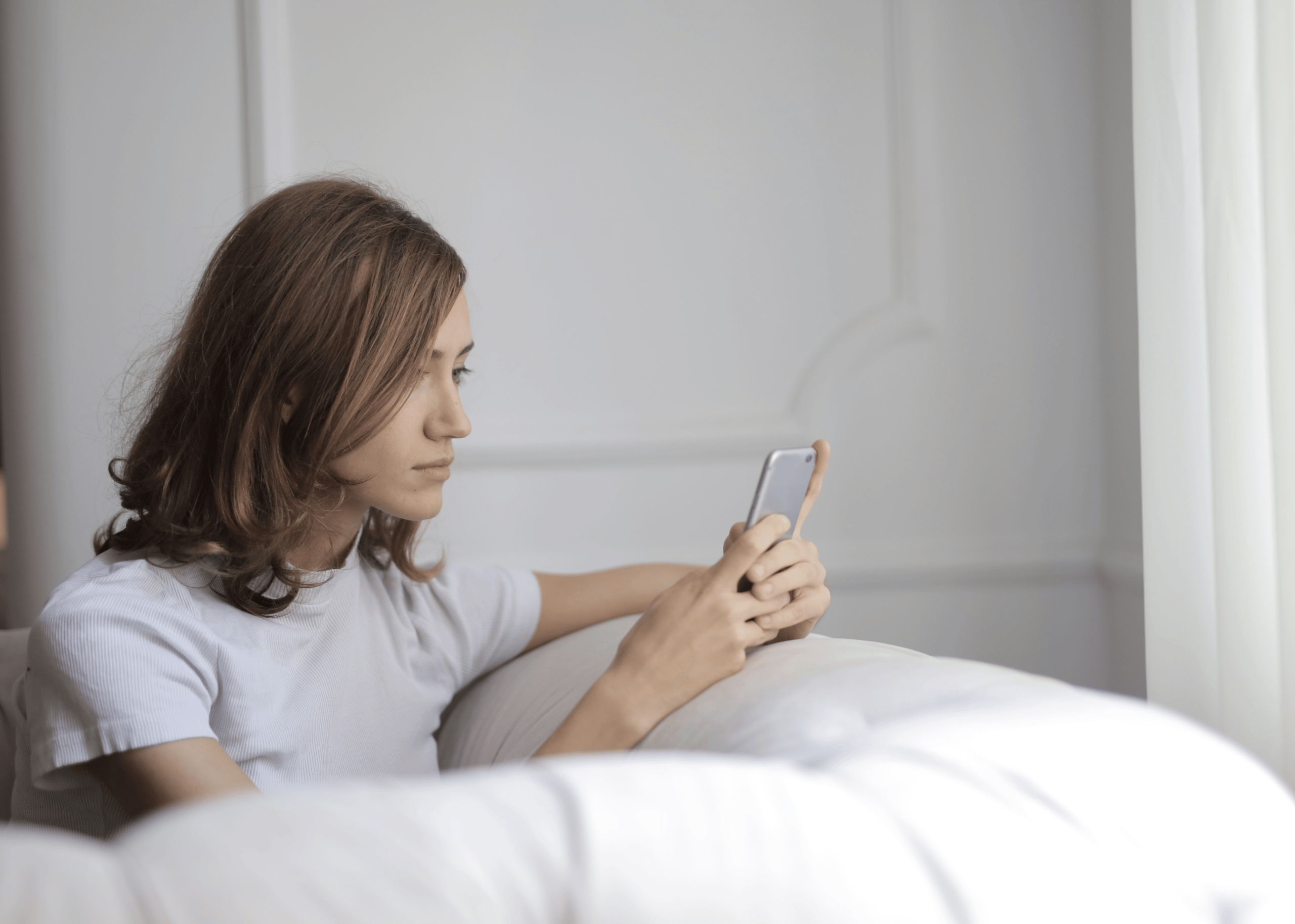 Woman reading a message on her phone with a focused expression, illustrating the moment just before the nervous system activates a fight, flight, freeze, or fawn response.