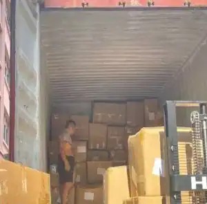 Worker loading cartons of gift bags into a shipping container at a China warehouse