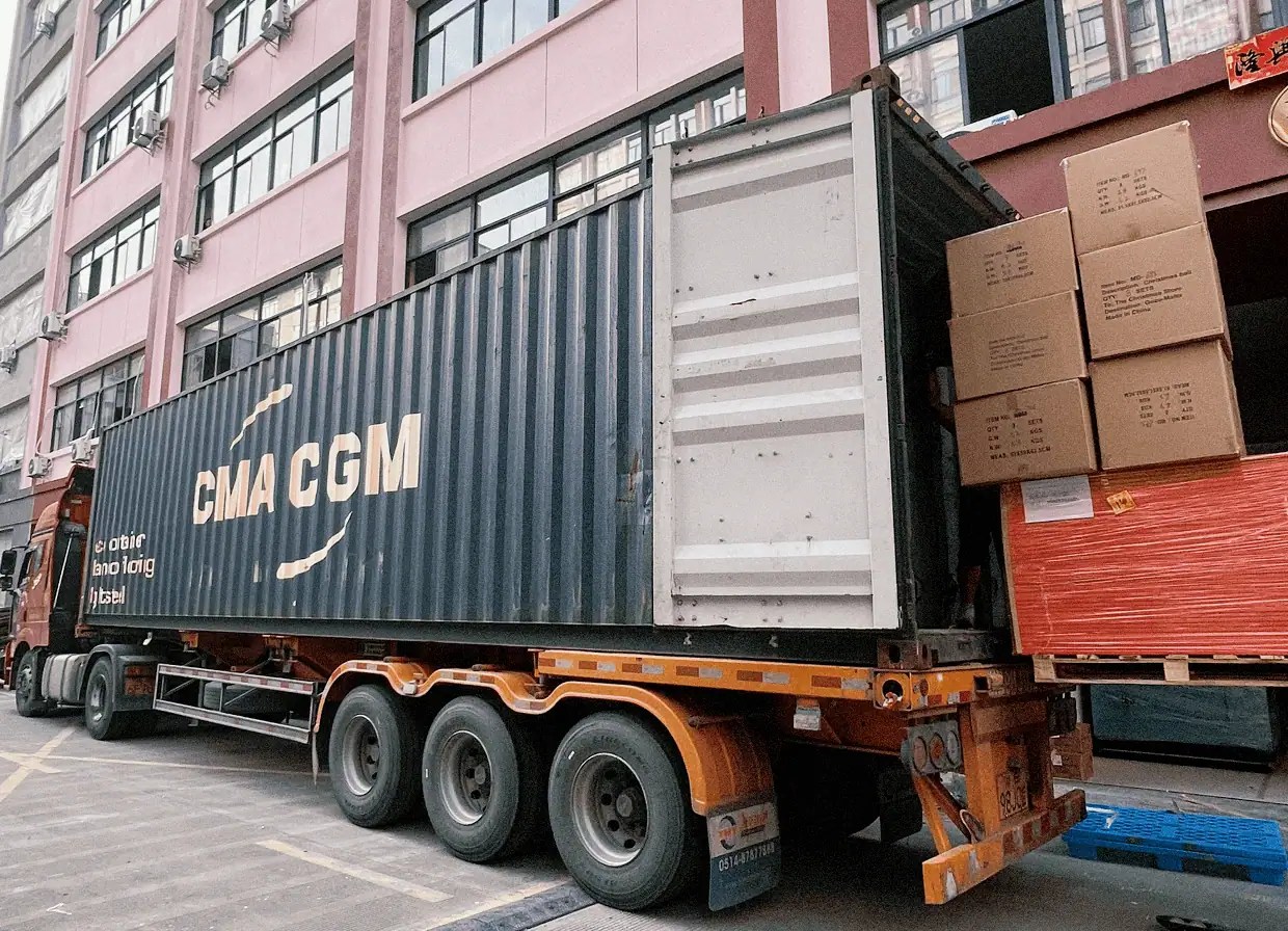 Flat wrapped panels and palletised cartons being loaded into a mixed furniture container at a warehouse in China