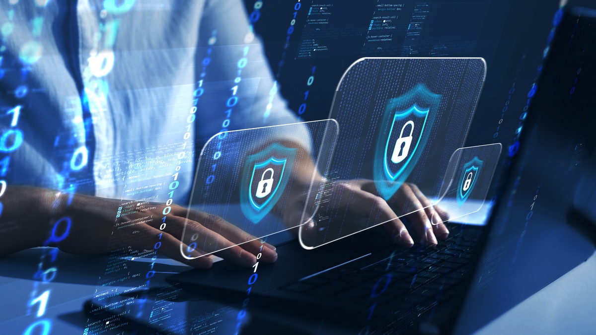 A person is typing on a keyboard, and the area has a blue hue. There are floating icons with a shield and lock.