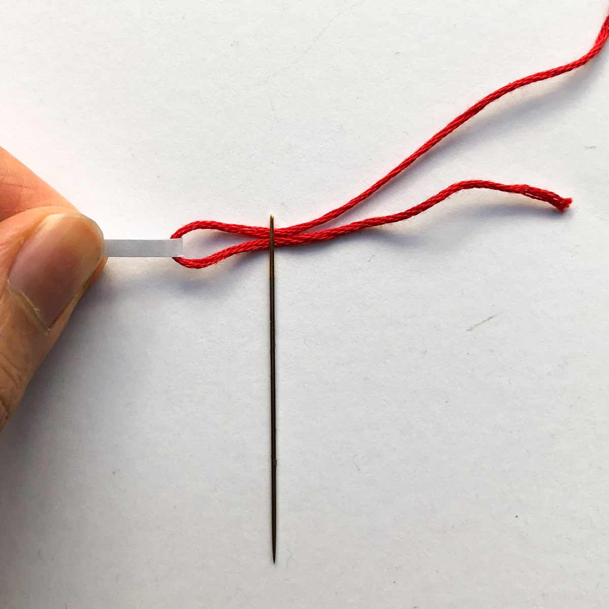 Pulling thread through eye of needle