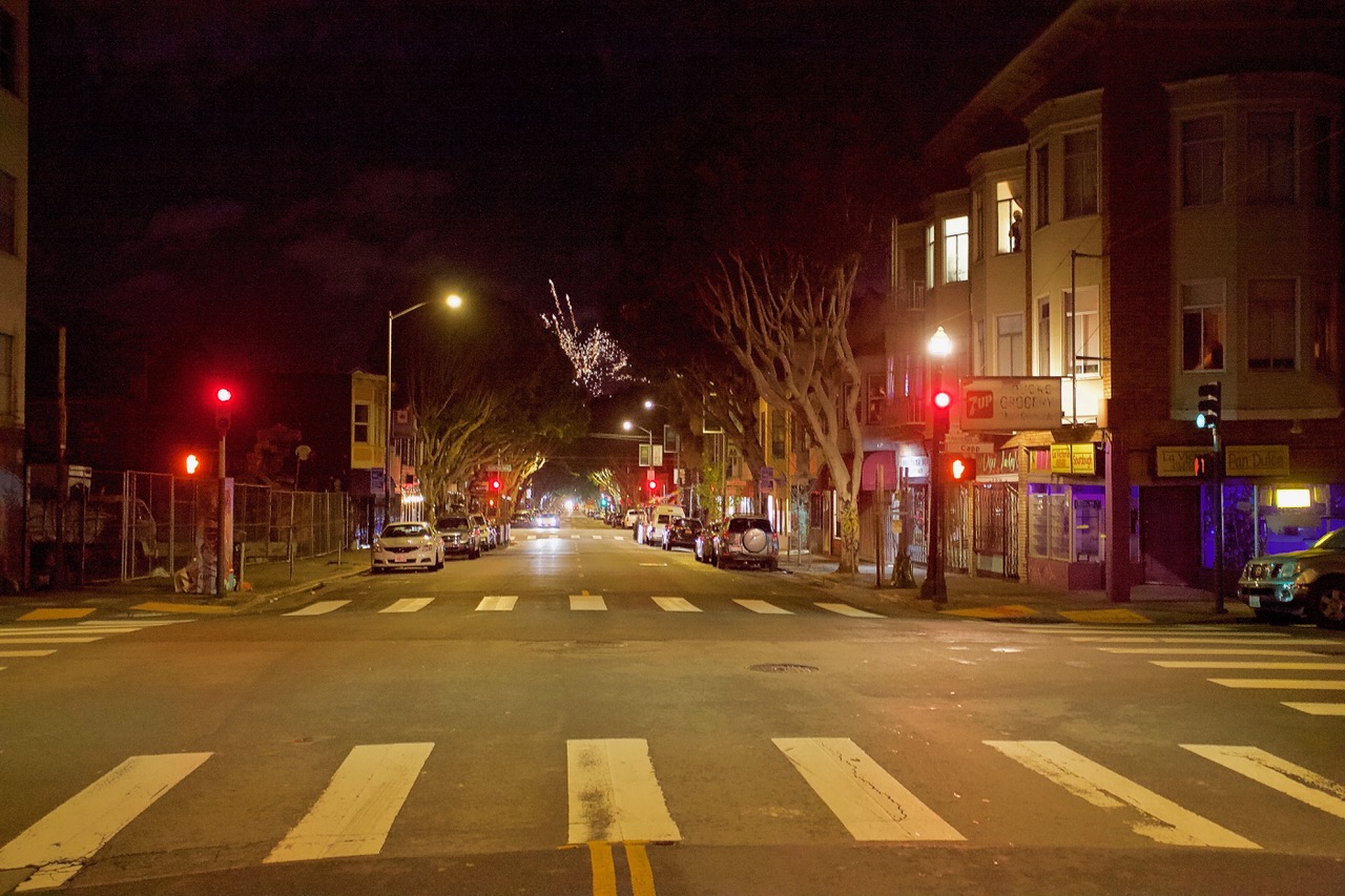 A street at night, crosswalk in the foreground and fireworks.