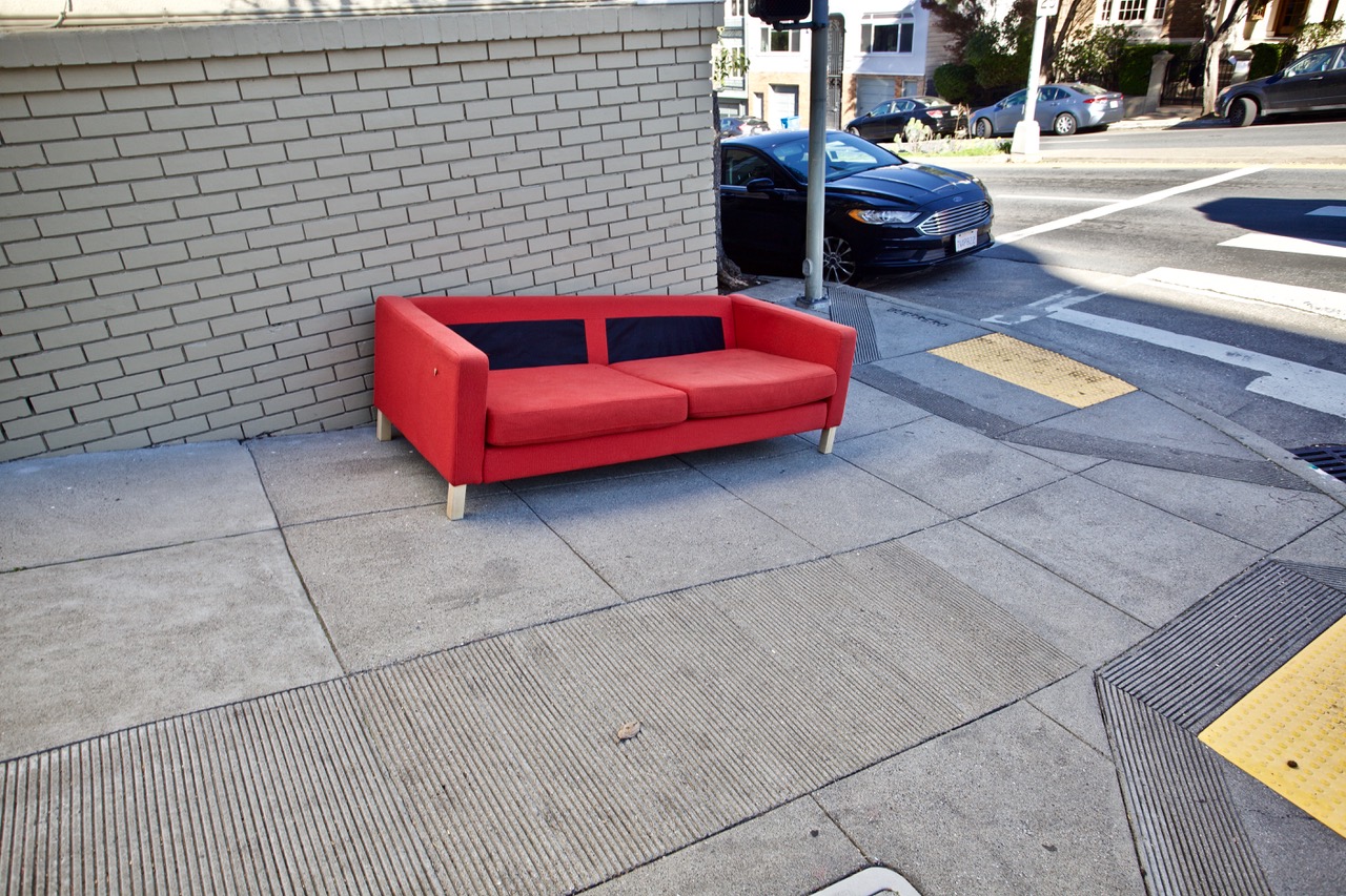 A red couch on the sidewalk.