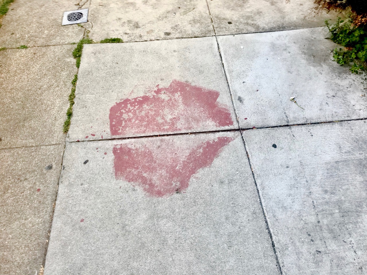 A large red smudge on the sidewalk .