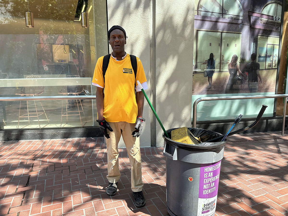 A man with a yellow shirt and trash can.