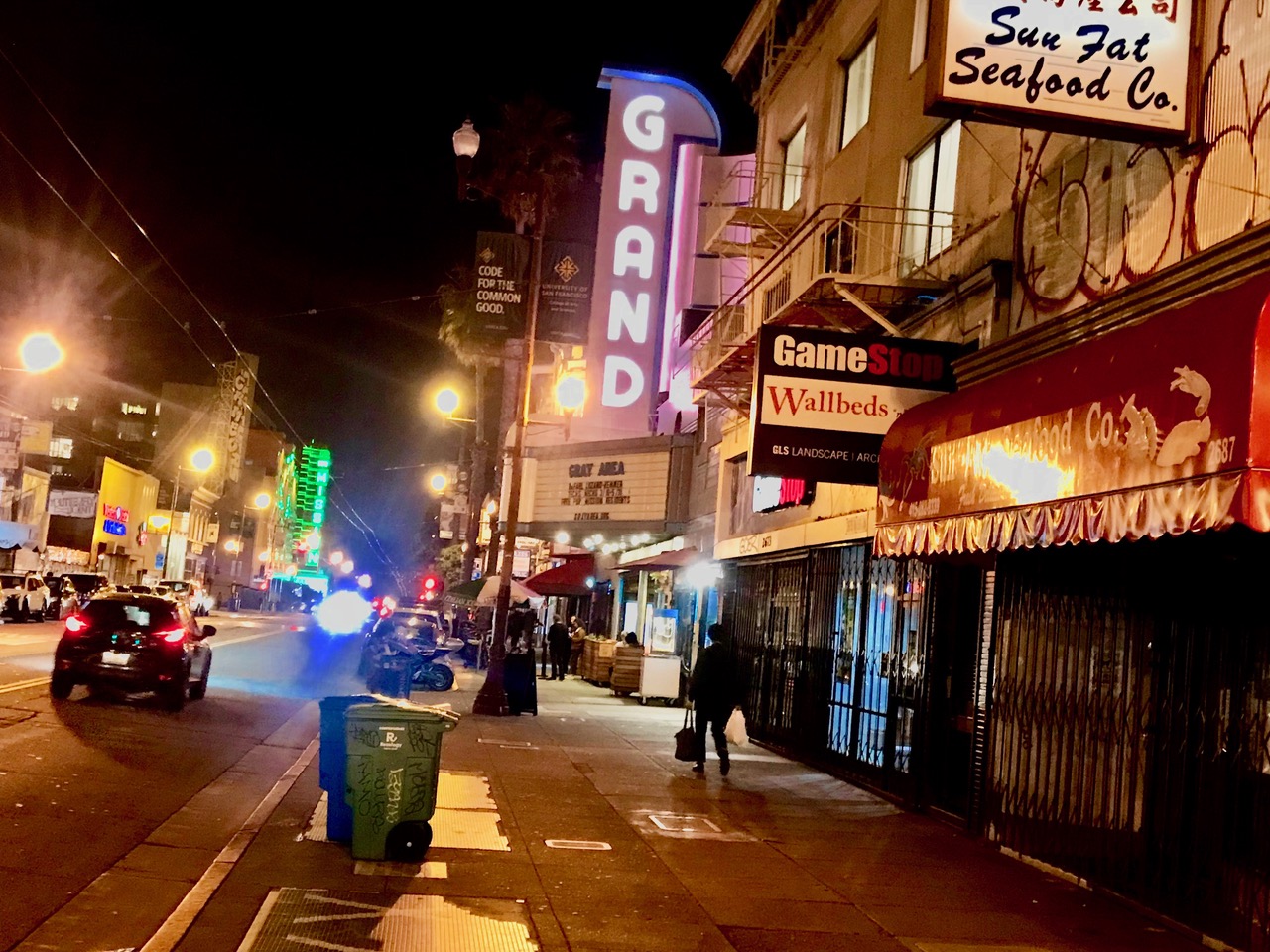 Street scene at night with lights lit up including neon lights.