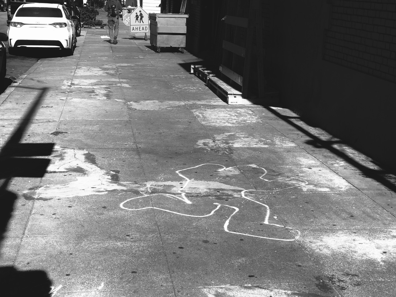 A sidewalk with a chalk outline of a body, a parked car, and a pedestrian near a “school crossing ahead” sign in the background.