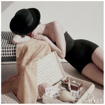 Model Anne St Marie wearing a black knit maillot by Catalina and a wide-brimmed beach bonnet by Brett Winston. July 1955 Glamour
