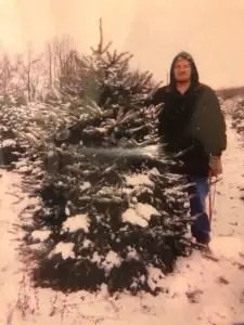 Family cutting a Christmas tree at a Michigan tree farm, a holiday tradition.