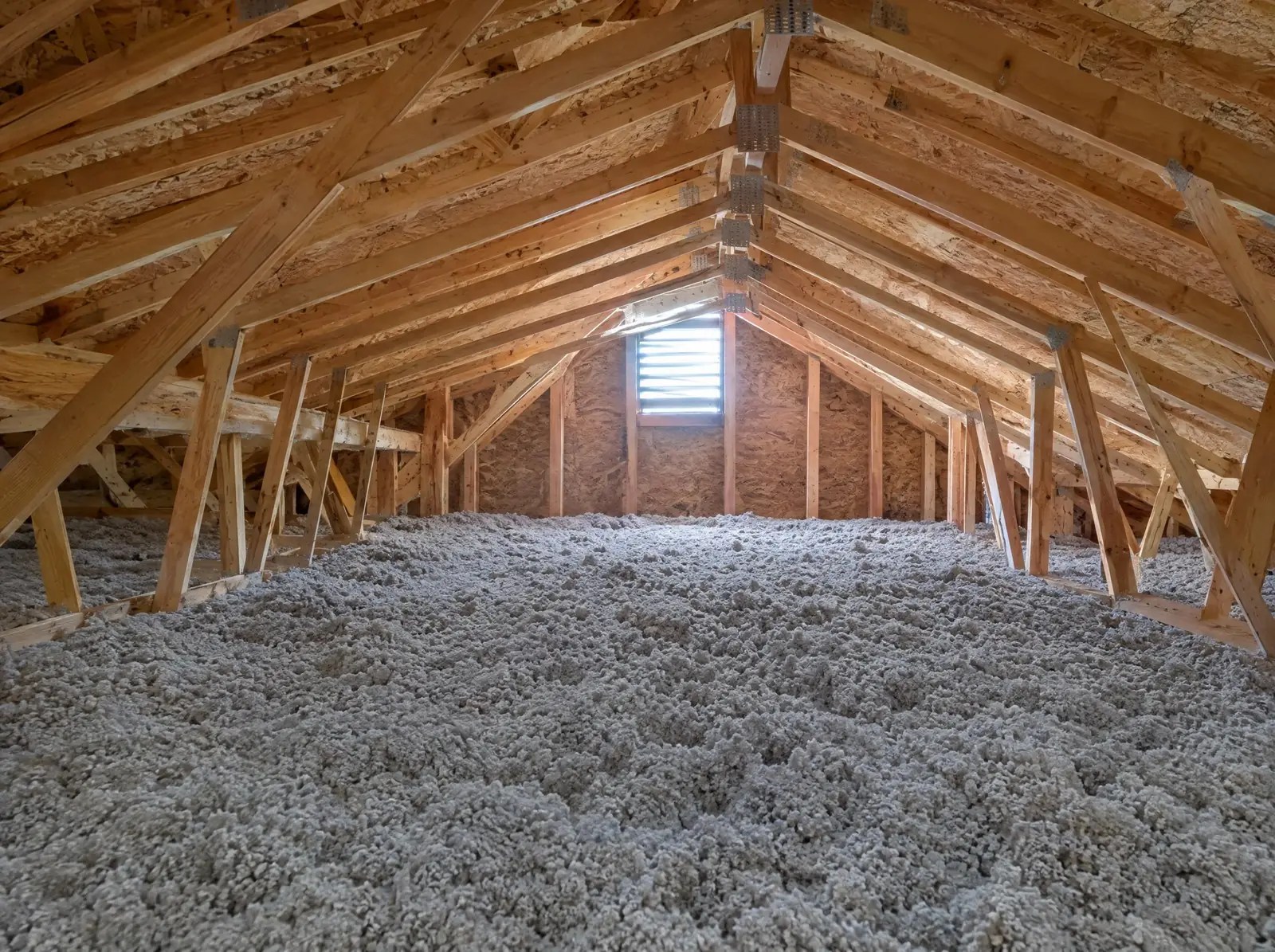 Blown-in cellulose insulation, deep and even, in an attic under the roof trusses