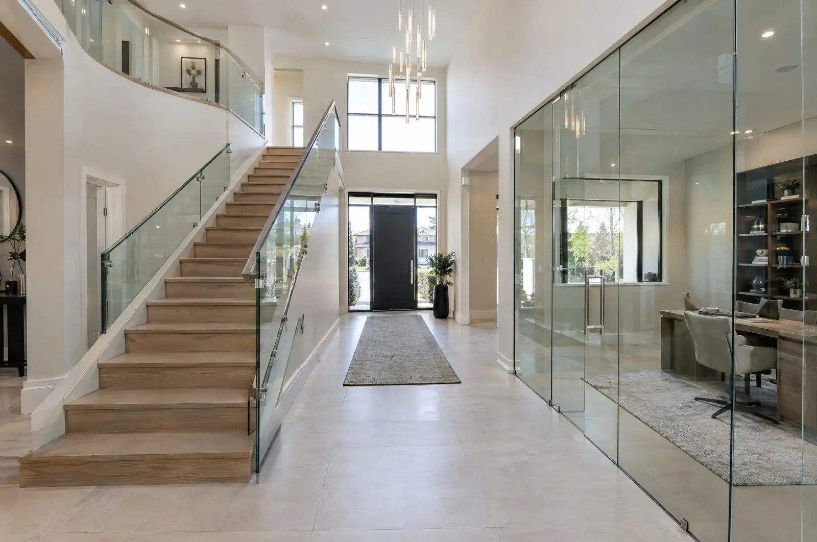 A two-storey foyer in a modern GTA home: curved glass railing, frameless stair guard and glass office wall