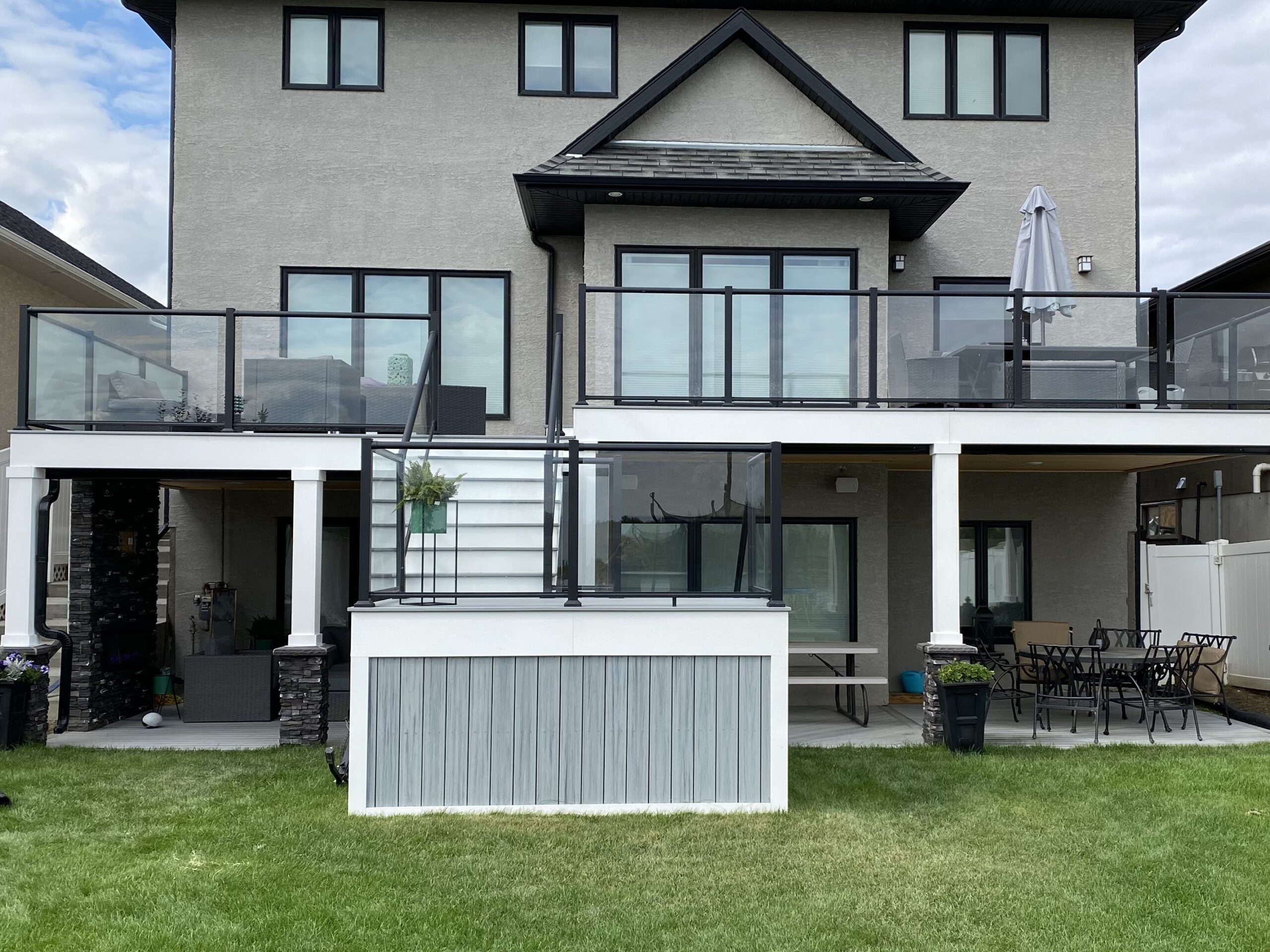 Large deck with two levels and stone pillars and glass railing