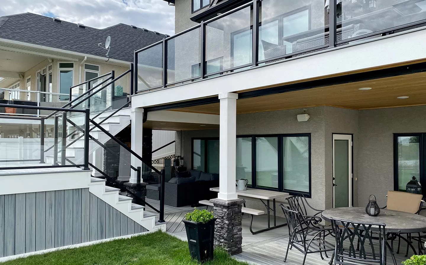 Multi-level composite deck installation with glass railing and pvc trim