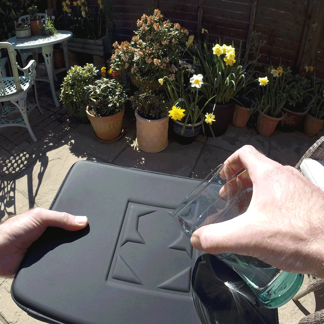 An animated gif of a hand pouring a glass of water over PROHOOD's EVA Leather outershell. MNK
