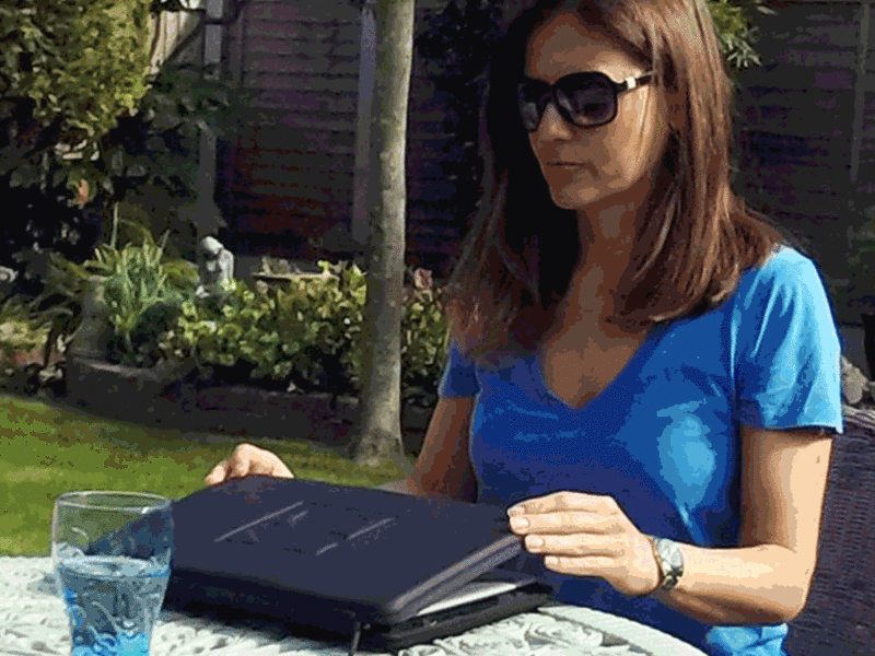 A animated gif of a girl unfolding hood of mnk case PROHOOD to use her laptop in a sunny garden. MNK