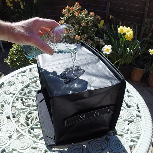 A hand pours water over the protective hood of PROHOOD. MNK