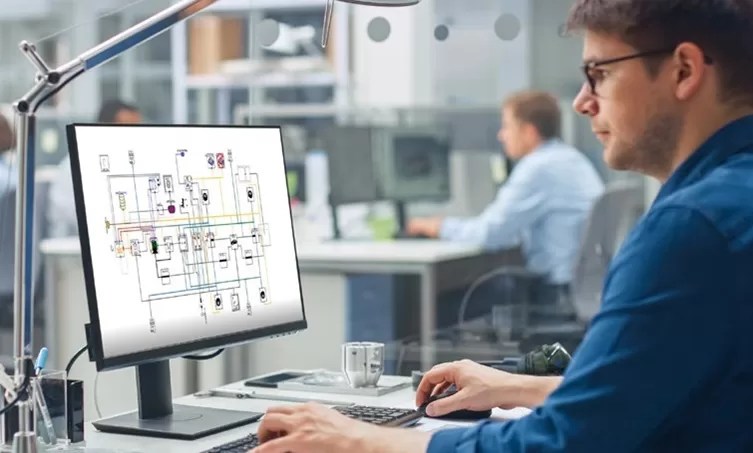 Engineer working on electrical schematic design using CAD software in modern office environment.