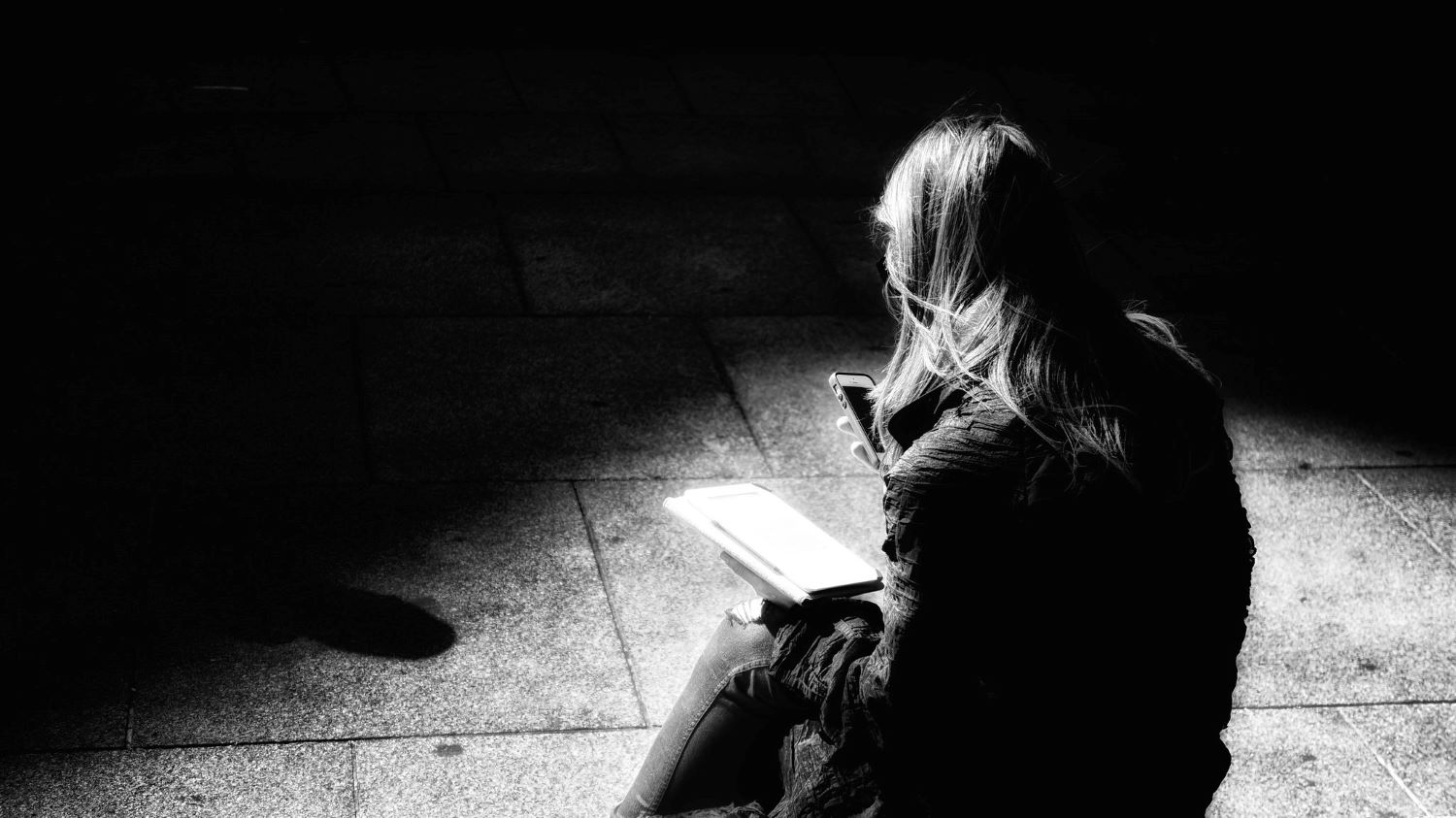 Woman sitting on the ground looking at her phone.
