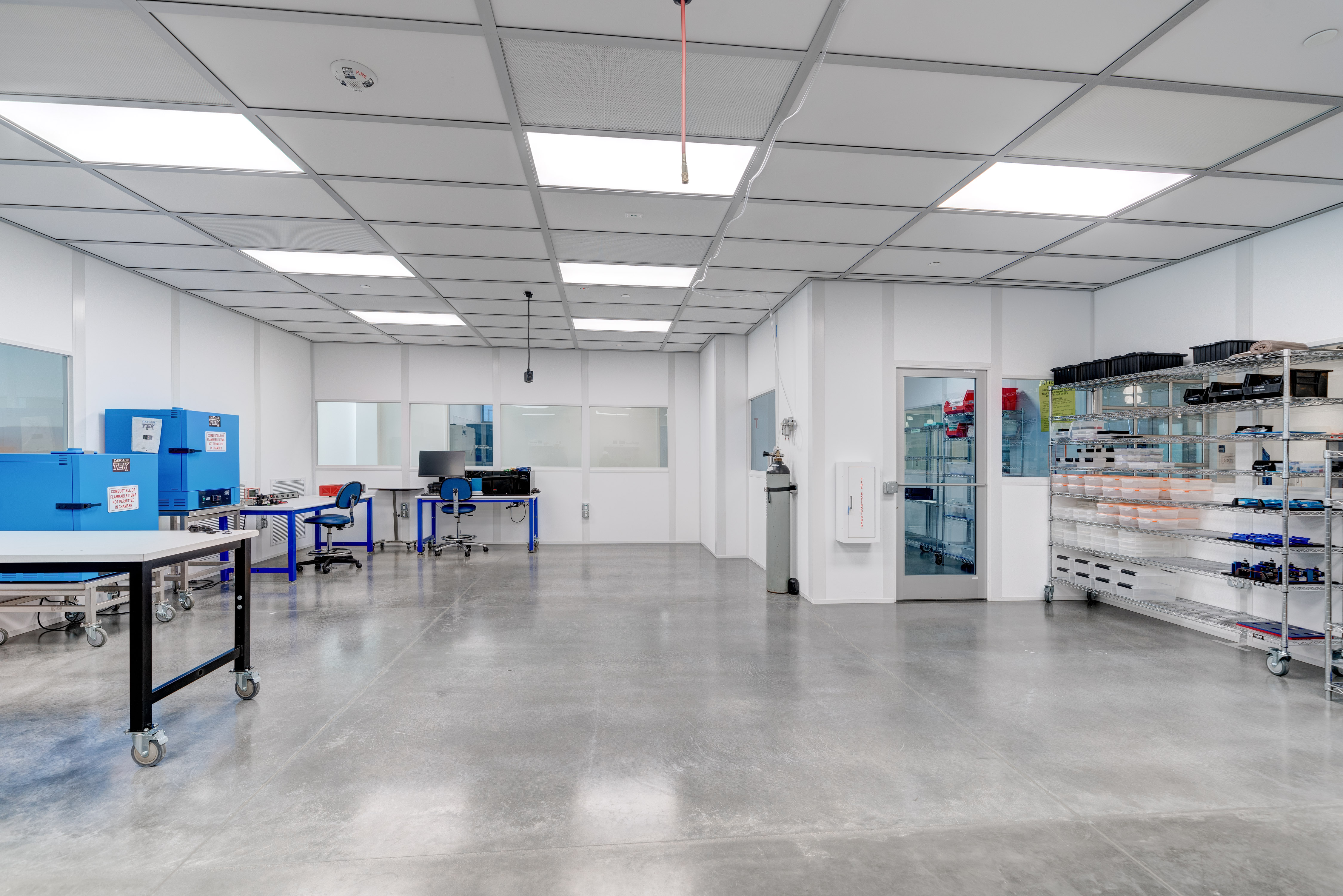 Clean, modern laboratory workspace with bright lighting, workstations, and organized shelving.
