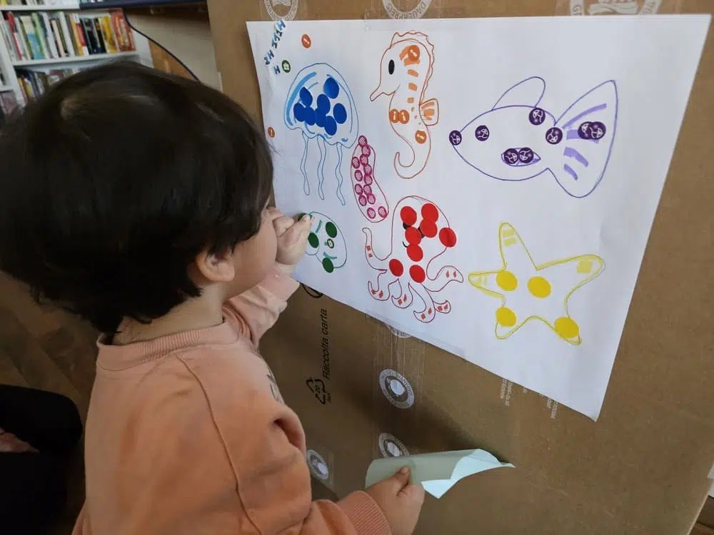 toddler doing ocean sticker activity placing dot stickers on sea animals
