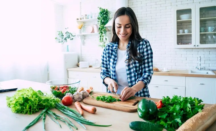 Woman cooking fresh vegetables at home to show how to save money by eating out less