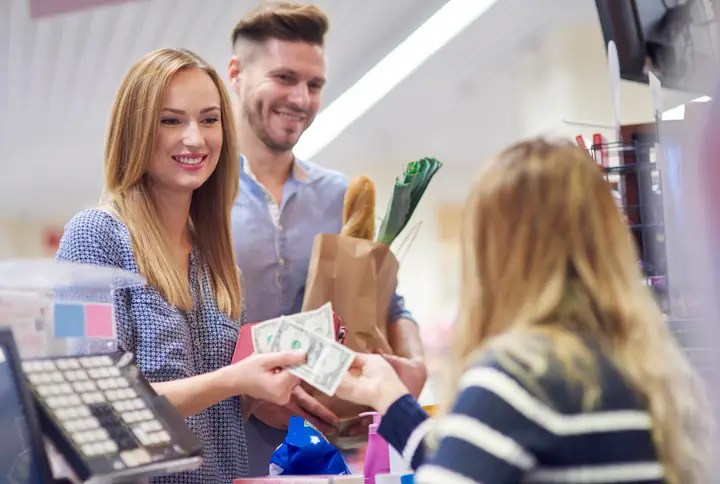 shoppers using cash at a store counter to budget expenses – how to use cash to save money
