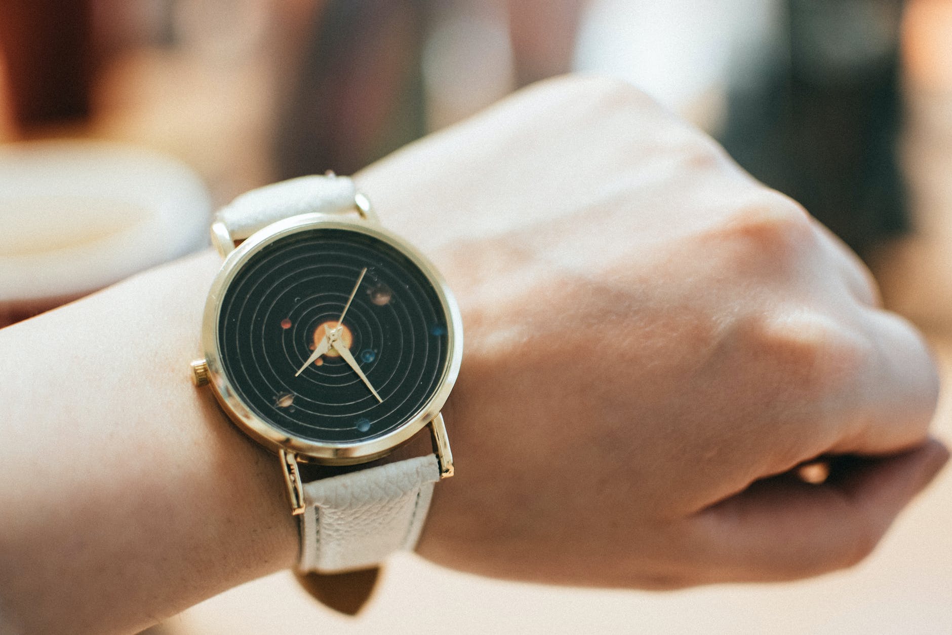 round gold colored black analog watch with grey leather band
