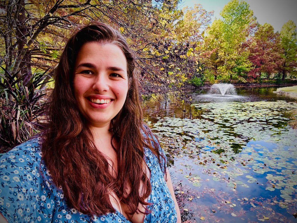 Selfie of author Laura Teichen in front of a pond at a botanical garden