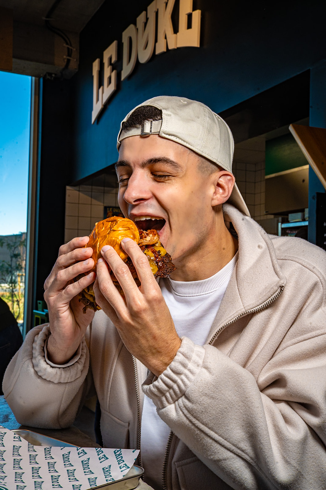 Personne en train de manger un smash burger du Duke au complexe MOOV