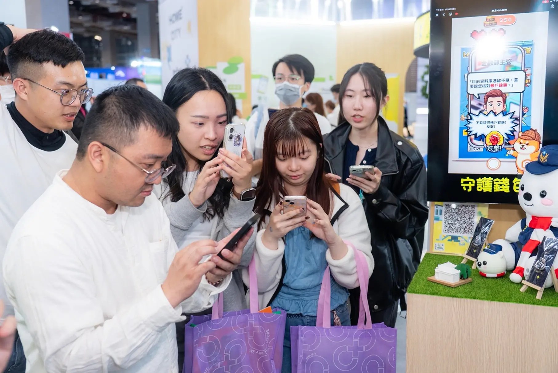 民眾在南港展場使用手機體驗廢柴探長AR防詐互動遊戲。