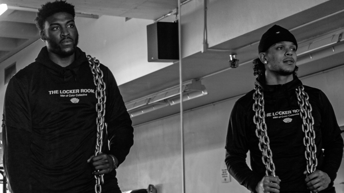 Two student athletes holding chains staring into a mirror.