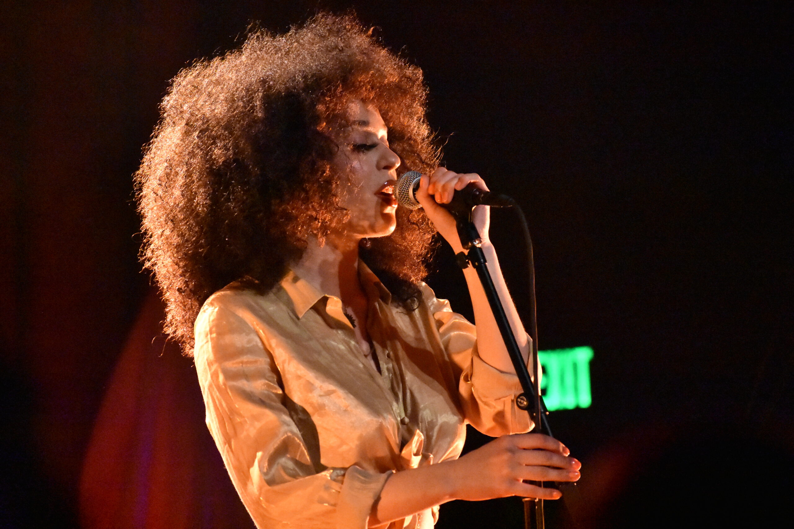 Steele sings into a mic with a passionate expression