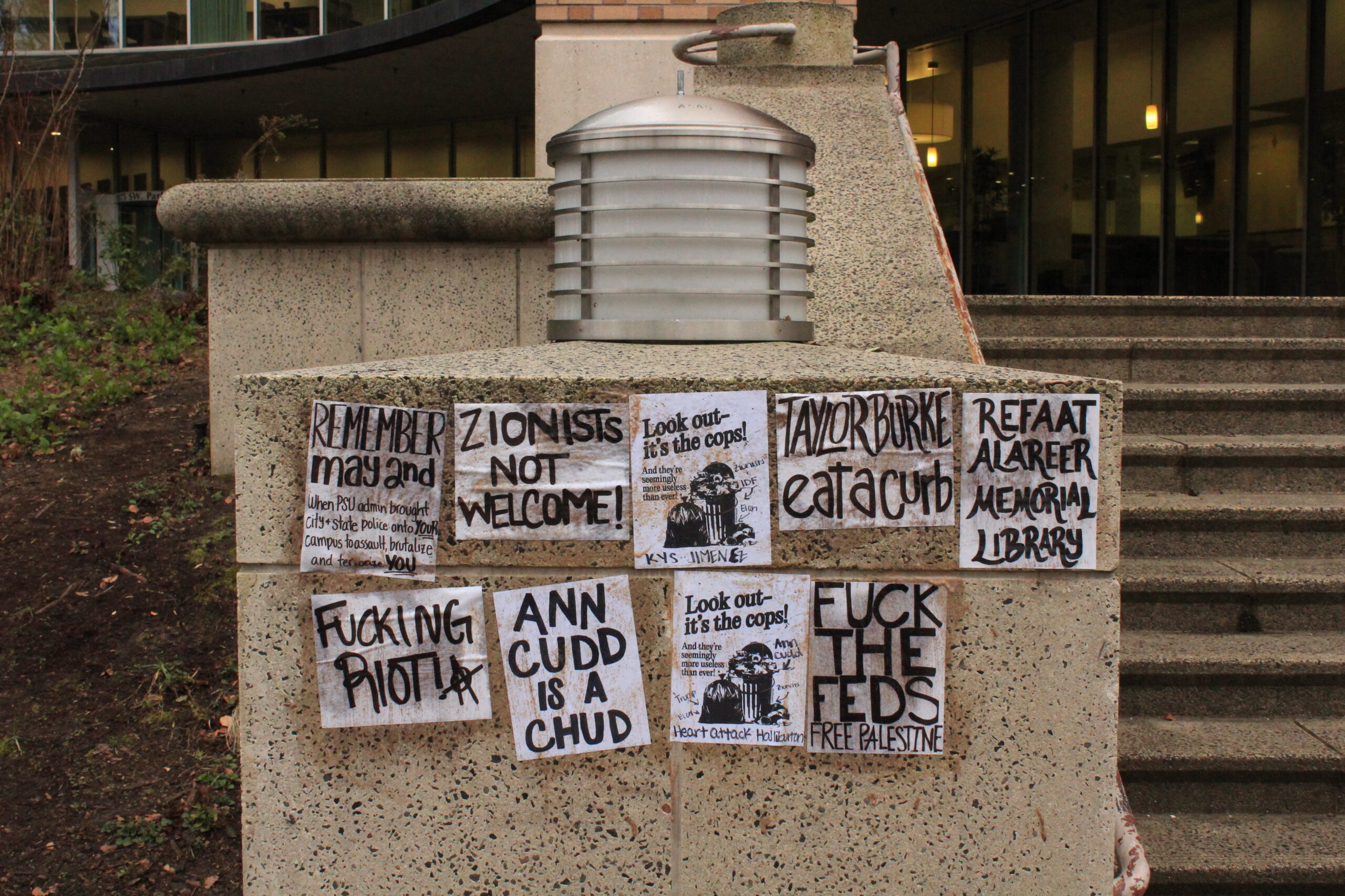 Posters in protest of PSU President Ann Cudd with pro-Palestine messages hang on the stairs of Millar Library.