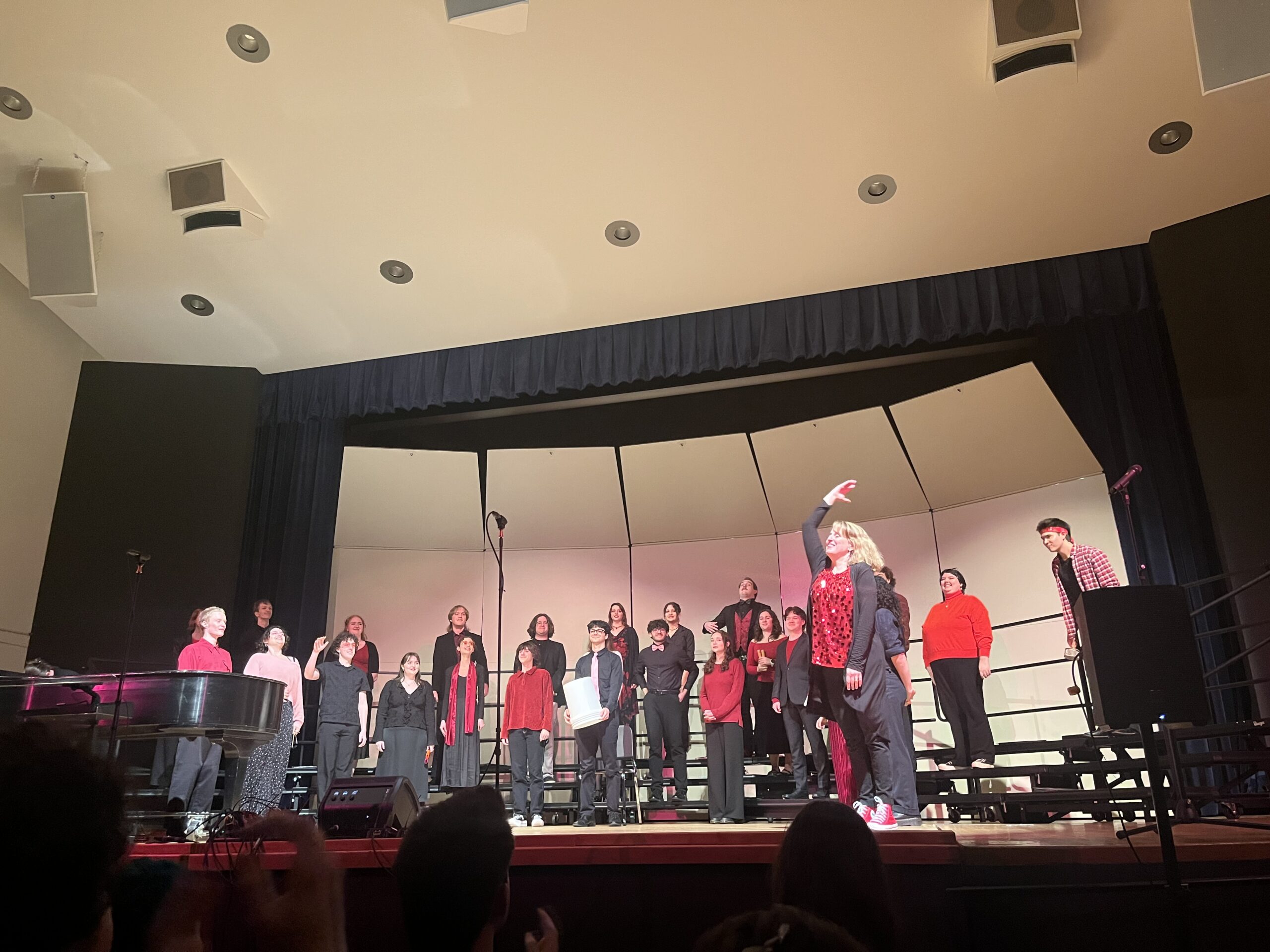 Choir sings as the director holds hand up with emotion.