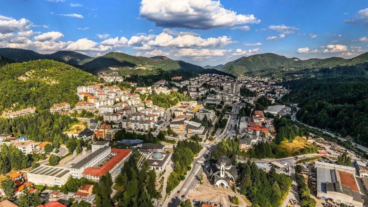 Aerial view of a town spread through a wooded valley in the Rhodope Mountains