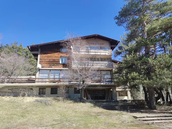 Chernatica hut, a timber and render building with balconies among leafless early-spring trees