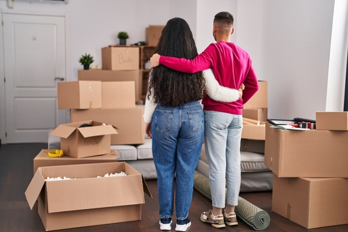 young couple staring at boxes in their new home to illustrate thinking about their new home checklist