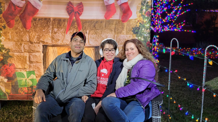 A family of three sit in front of a fireplace facade on a lawn in Winterhaven in Tucson. MPA Project Travels.