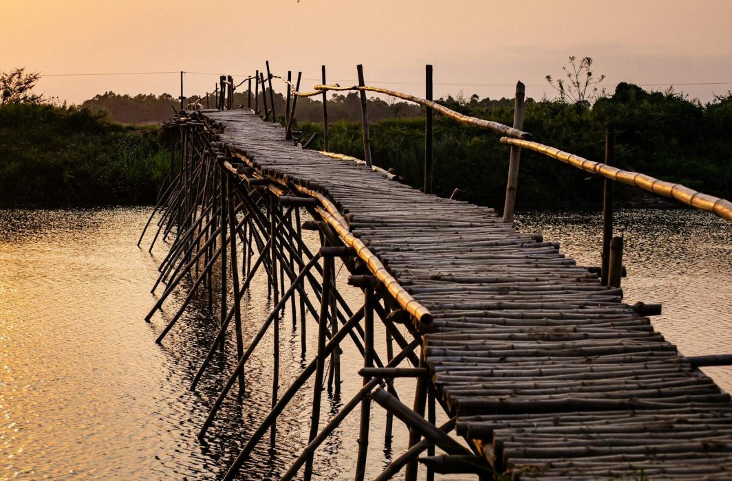 Captivating view of a bamboo bridge over a river at sunset in Hội An, Vietnam.