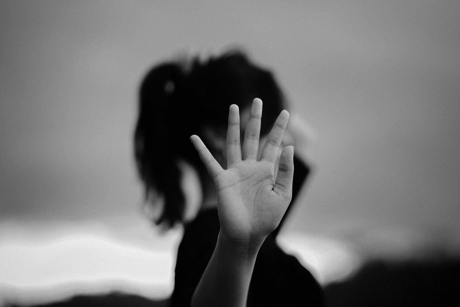 Black and white photo of a person showing an open hand in a gesture, evoking emotion.