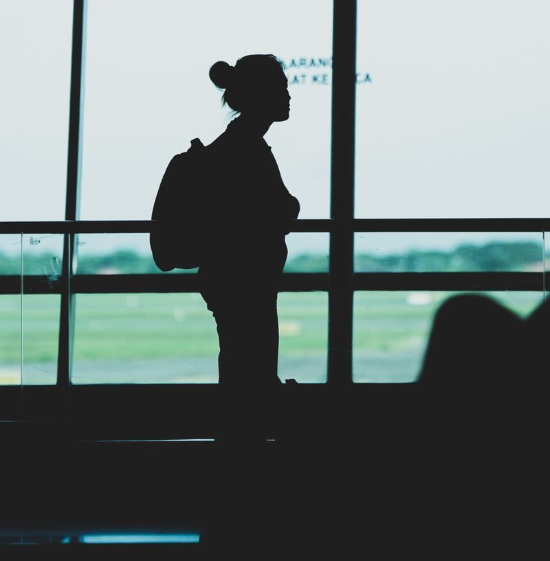 Silhouette of a woman with a backpack standing at Surabaya airport terminal, Indonesia.