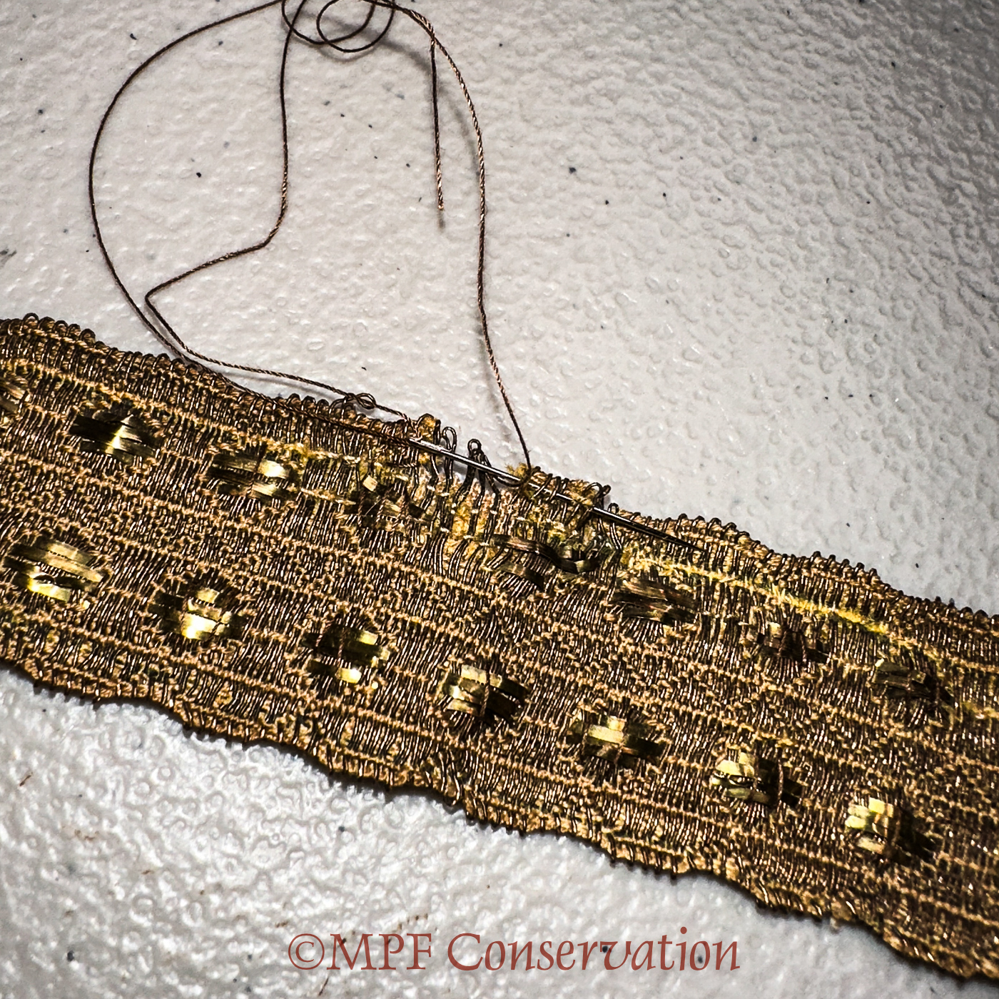 Weaving through historic metallic stitches with brown thread...