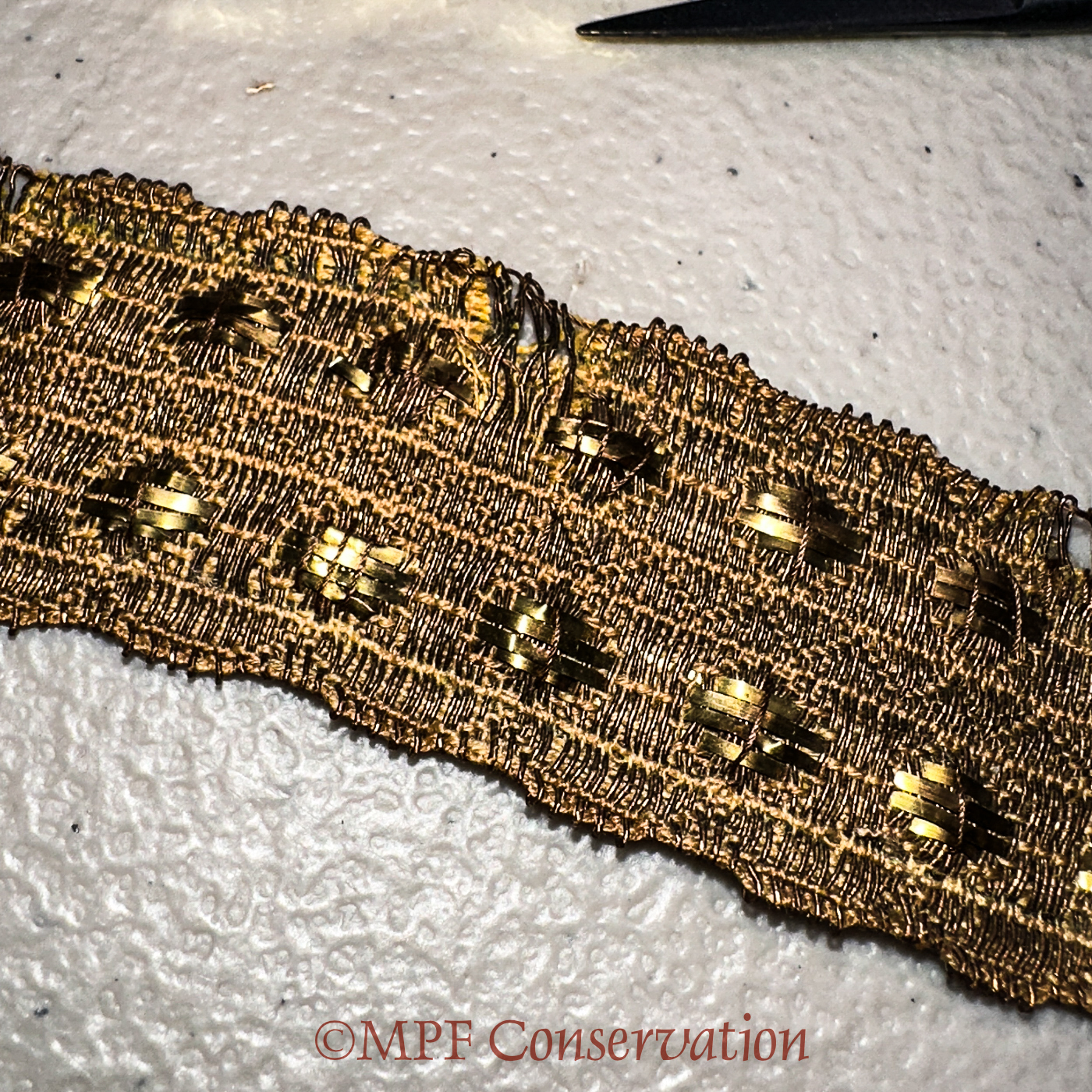 Detail showing the cross stitching of the brass to secure.