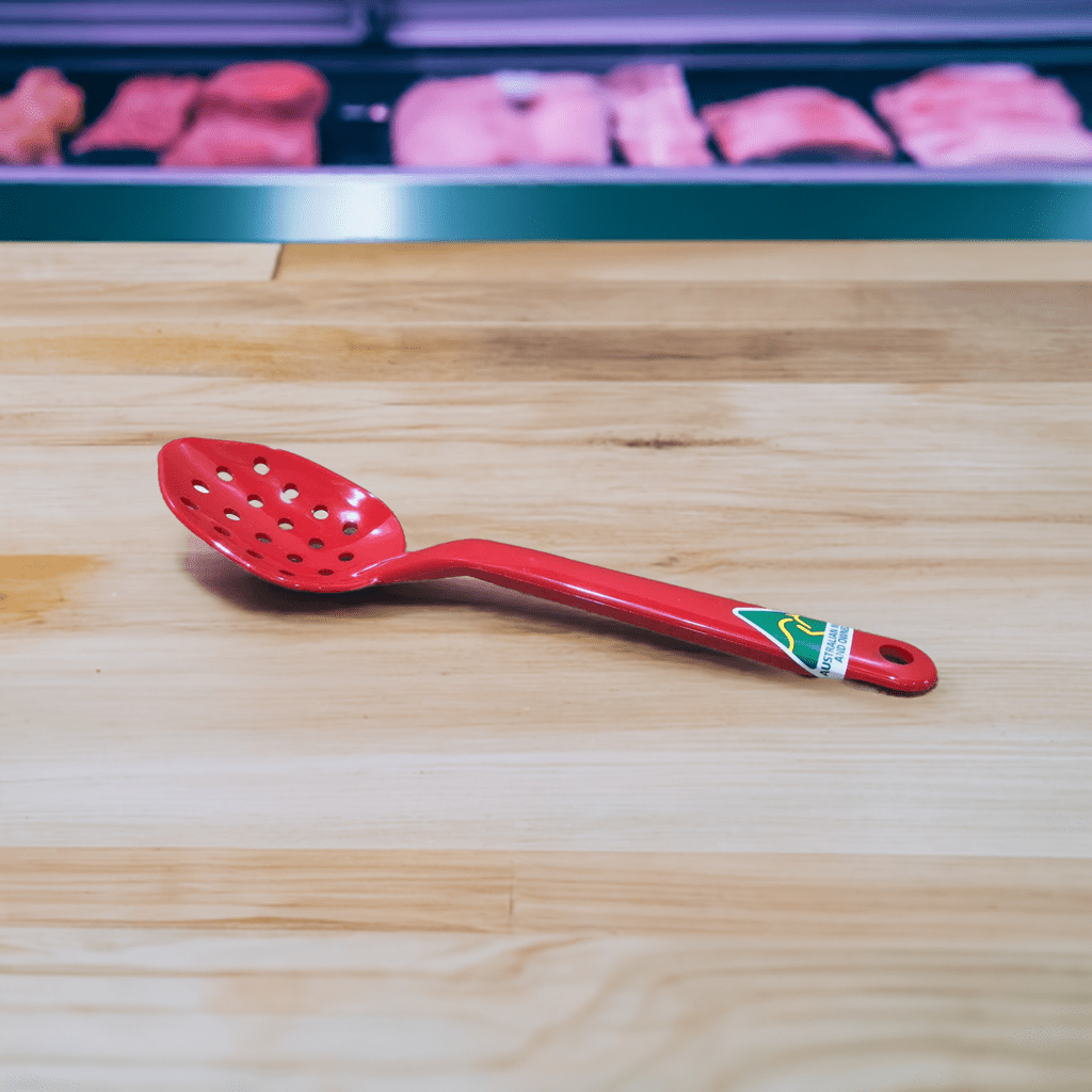 Red slotted spoon on wooden surface, showcasing MTA Products' durable kitchenware, designed for food preparation and presentation.