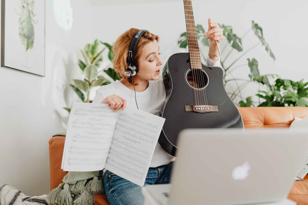 woman playing guitar on video call on computer