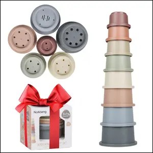 A stack of eight pale multicolour toy cups of decreasing circumference next to six of them in a group (showing their perforated bases) and an image of the original packaging tied with a red bow.