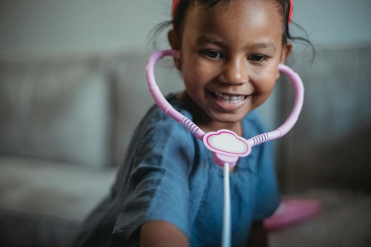 playful asian girl with pink toy stethoscope