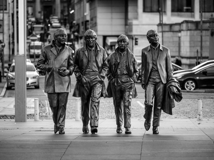 the beatles statue on a street in liverpool in black and white