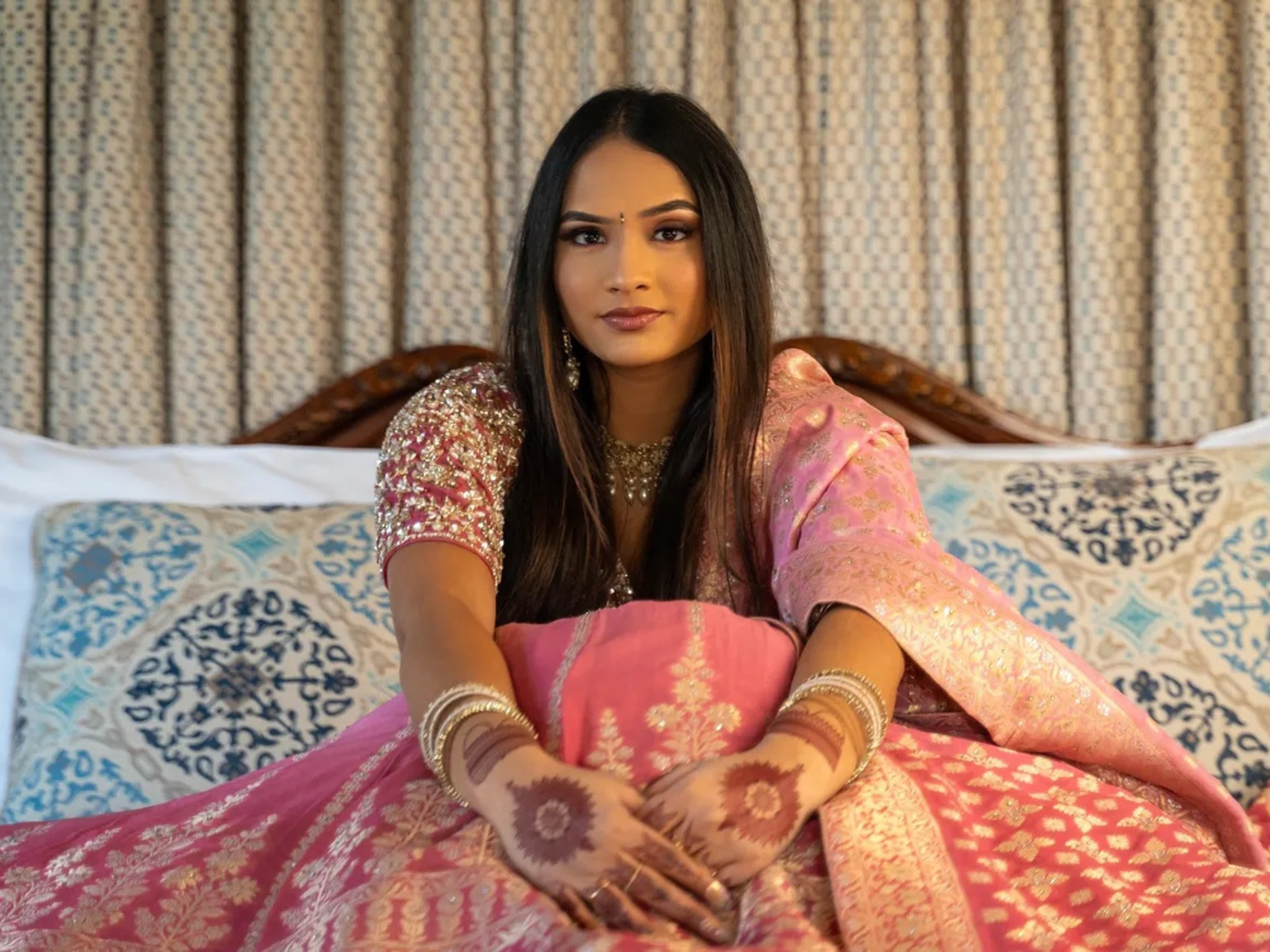 A photo of artist Saloni. She is sitting in a bed with sumptuous fabrics.